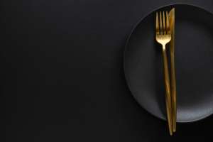 golden-cutlery-with-textile-plate-dark-background-top-view